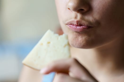 Closeup of crop unrecognizable teenage girl holding eaten cheese slice at home