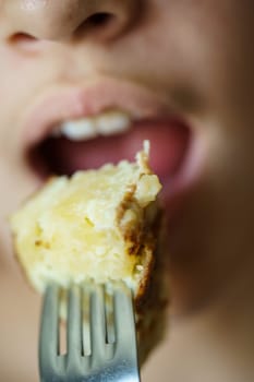 Closeup of crop anonymous young girl about to eat delicious potato omelette from fork at home