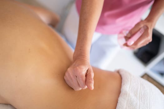 From above of crop anonymous therapist massaging back of patient during rehabilitation session in clinic