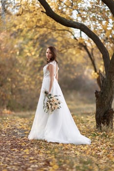 beautiful happy bride holding wedding autumn bouquet in nature