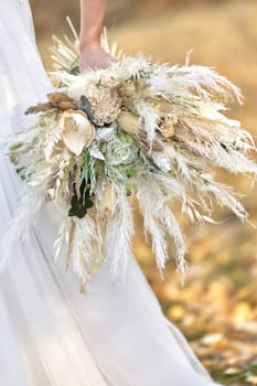 hands of the bride holding beautiful autumn bouquet outdoor