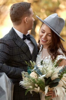 beautiful happy stylish bride in hat and groom laughing outdoor