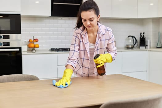 young woman cleaning and wiping wooden table with microfiber cloth. chores at home. Housekeeping
