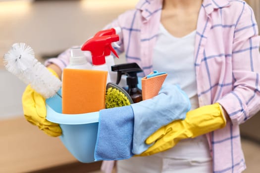 Woman in rubber protective yellow gloves holding cleaning tools. house chores.