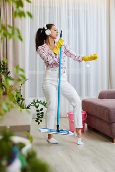 Happy woman singing and washing floor at living room, house chores.