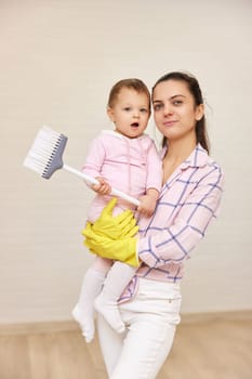 happy mother housewife is holding cute baby girl and doing housework at home, Happy family