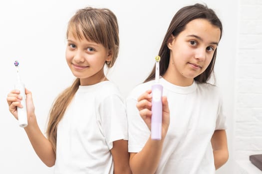 Portrait of two beautiful girls kids with perfect smile holding toothbrushes. Child dental care, oral hygiene concept. High quality photo