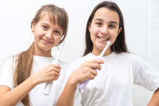 Portrait of two beautiful girls kids with perfect smile holding toothbrushes. Child dental care, oral hygiene concept. High quality photo