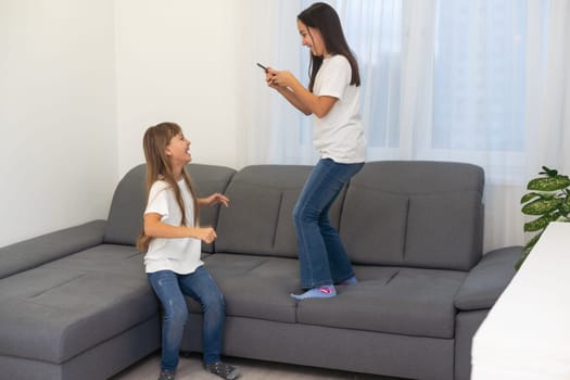 people, technology and friendship concept - happy teenage girls taking selfie with smartphone sitting on sofa at home. High quality photo