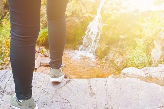 Female hiker walking in mountains forest. Beautiful brook, waterfall in the mountains in the forest.