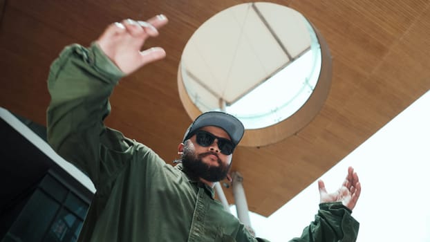 Motion shot of asian handsome hipster pose in hip hop style while looking at camera. Low angle image of professional street dancer dance in freestyle movement at mall. Outdoor sport 2024. Endeavor.