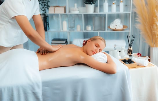 Caucasian woman customer enjoying relaxing anti-stress spa massage and pampering with beauty skin recreation leisure in day light ambient salon spa at luxury resort or hotel. Quiescent