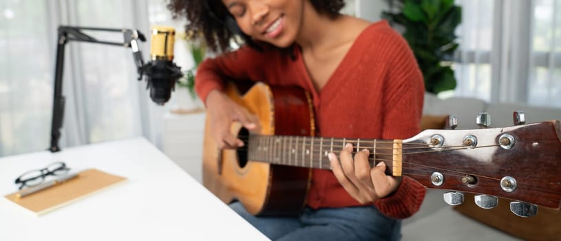 Host channel in musician of young African American playing guitar along with singing, broadcasting on smartphone in studio. Decoration of equipment headsets and recording microphone. Tastemaker.