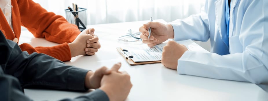 Couple attend fertility consultation with gynecologist at hospital as part family planning care for pregnancy. Loving husband and wife support each other through the doctor appointment. Panorama Rigid