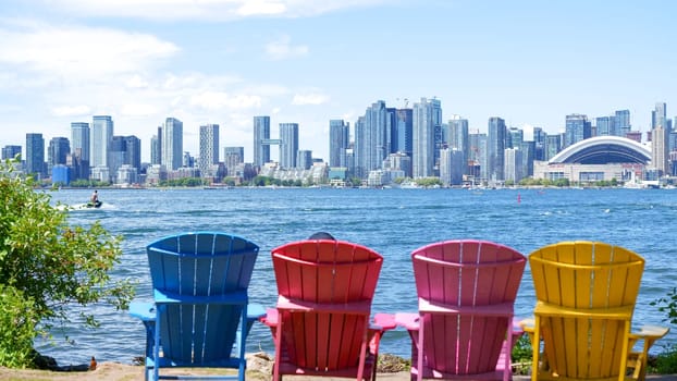 Panoramic view of Toronto skyline, Lake Ontario with colorful chairs on a sunny day, Toronto, Ontario, Canada