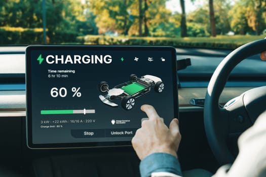 Electric car driver checks battery charging status, range and charging limit on app screen in the car. Smart technology device show EV car recharging data of electric storage in car battery innards.