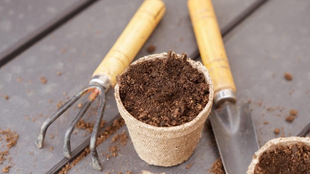 Close up of eco friendly biodegradable peat pots and garden tools, top view, selective focus. Spring natural gardening, eco, plant care, organic product.