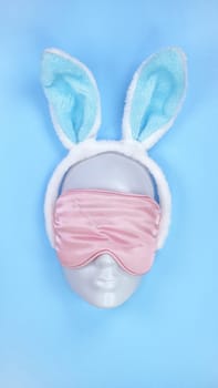 Pink sleeping eye mask on mannequin face with christmas horns on blue background, sleeping disorder. Holidays, Head accessory. Plastic face