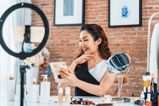 Asian Woman influencer shoot live streaming vlog video review makeup uttermost social media or blog. Happy young girl with cosmetics studio lighting for marketing recording session broadcasting online