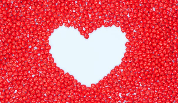 Big heart lined with candy hearts on light blue background. Pink, white, red hearts. Peppermint candy love. Valentine Day. Lots of little hearts. Copy space for text. Banner