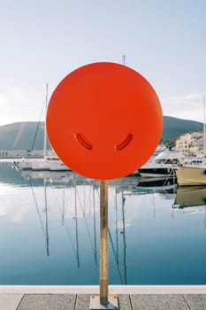 Life buoy in a box stands on a pier with moored yachts. High quality photo
