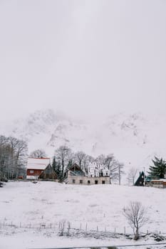 Snow-covered house under construction in a small village at the foot of the mountains. High quality photo