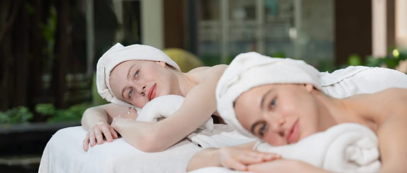 A portrait of a couple of a beautiful young caucasian woman with white towel rest on comfortable spa bed with relaxation while having body massage with professional masseur at spa salon.Tranquility.