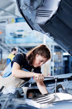 Technician in car service uses torque wrench to tighten bolts after replacing engine. Diligent auto repair shop employee uses professional tools to fix customer automobile