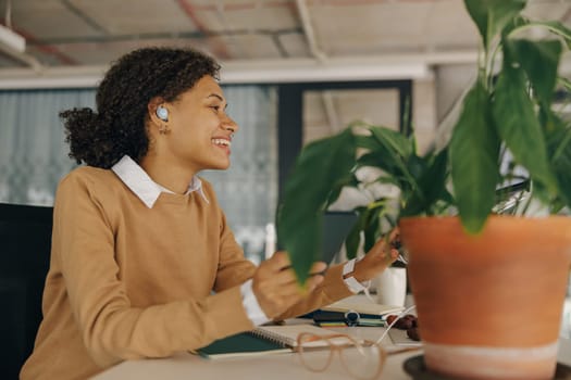 Smiling female manager is listen music in headphones during break time in office. High quality photo