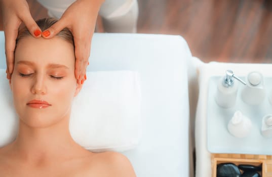 Panorama top view of woman enjoying relaxing anti-stress head massage and pampering facial beauty skin recreation leisure in dayspa modern light ambient at luxury resort or hotel spa salon. Quiescent