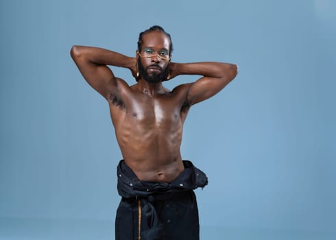 Confident shirtless african-american gay with bright makeup isolated on blue background, Gay African muscular macho man wearing make-up looking at camera.