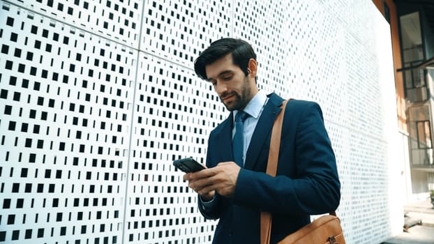 Smart manager looking at mobile phone and walking at street while wearing suit. Skilled investor looking mobile phone to checking sales or working while holding coffee cup. White background. Exultant.