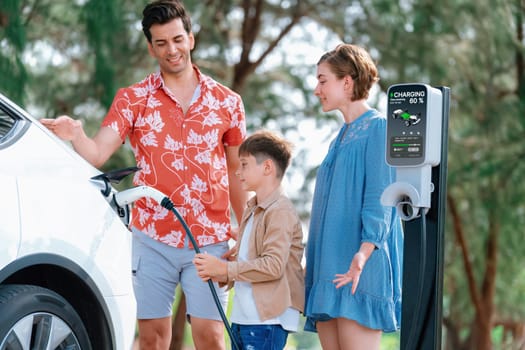 Outdoor adventure and family vacation camping in nature travel by eco friendly car for sustainable future. Lovely family recharge EV car with EV charging station in campsite. Perpetual