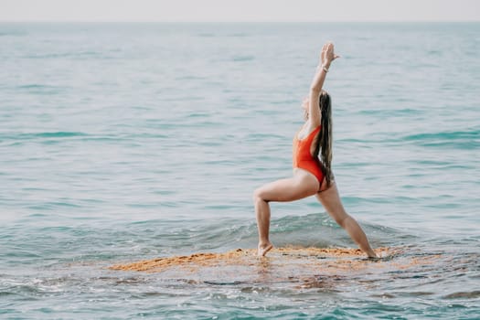 Woman sea yoga. Back view of free calm happy satisfied woman with long hair standing on top rock with yoga position against of sky by the sea. Healthy lifestyle outdoors in nature, fitness concept.