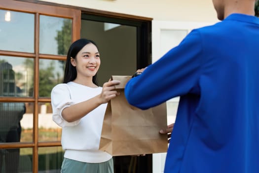 Asian young delivery man delivering package to female customer at home.