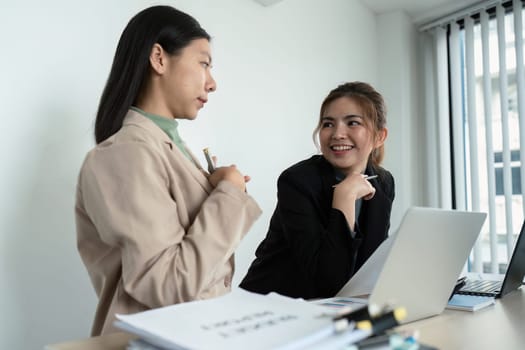 Employees discuss brainstorming planning business strategy on laptop at desk together in the office.