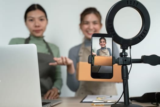 Beautiful asian woman showing clothes for sale in front of camera for live streaming at home.