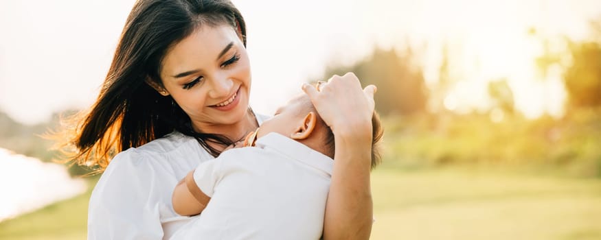 An intimate portrait of mother holding her sleeping baby in park at twilight. She smiles with pure joy, savoring tranquil moment in nature with newborn. heartwarming depiction of family care and love