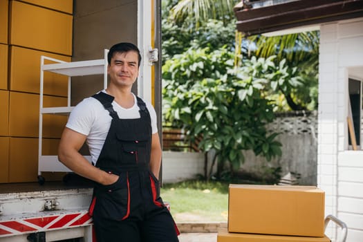 Portrait of a joyful mover working unloading boxes from a truck into a new home. These workers ensure a happy relocation and efficient service. Moving day concept