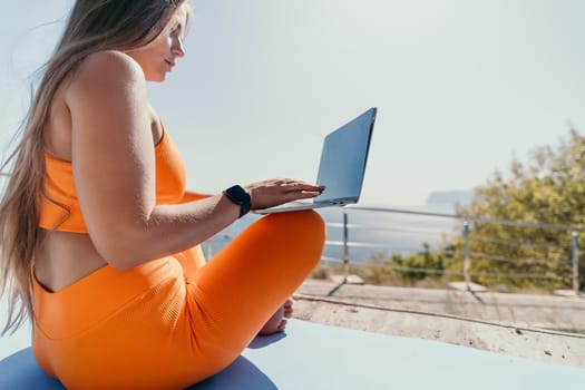 Digital nomad, Business woman working on laptop by the sea. Pretty lady typing on computer by the sea at sunset, makes a business transaction online from a distance. Freelance, remote work on vacation