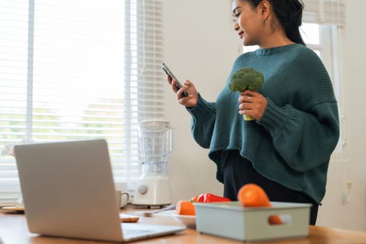 Beautiful smile fat woman cooking while using mobile phone in the kitchen at home.