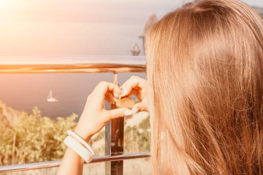 Hand, lock, heart, love, valentines day. Close up view of a woman holding a heart shaped lock that is locked onto a chain link fence.