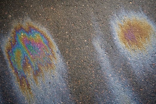 Oil or gasoline leaking from a car onto wet asphalt. Abstract background.