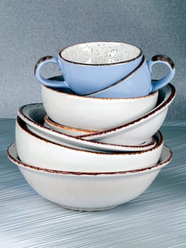 Ceramic bowls and cups are stacked on top of each other.