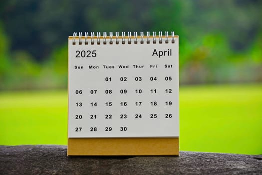 April 2025 white calendar with green blurred background - New year concept.