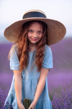 Girl lavender field. Laughing girl in a blue dress with flowing hair in a hat stands in a lilac lavender field.