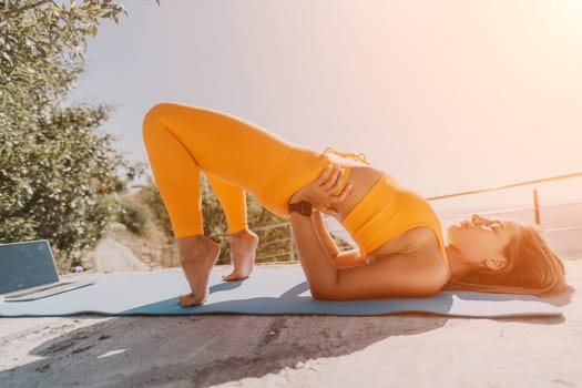 Fitness woman sea. Outdoor workout on yoga mat in park near to ocean beach. Female fitness pilates yoga routine concept. Healthy lifestyle. Happy fit woman exercising with rubber band in park.