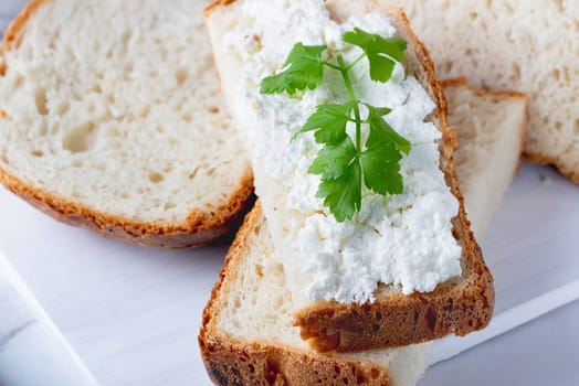 Bread with curd cheese on wooden board.