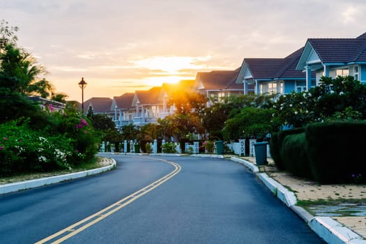 Modern cottages row road sidewalk two story buildings residential villas village New Estate Reflection dawn Sun in windows.