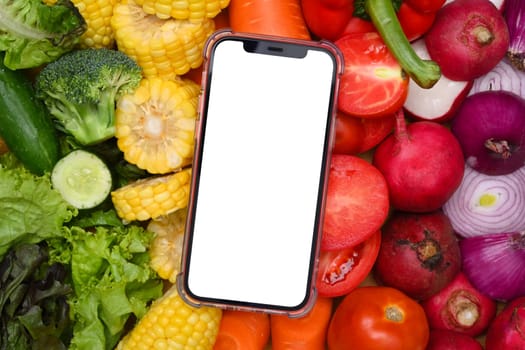 Smartphone with white screen over fresh vegetables. Delivery fresh food and nutrition concept